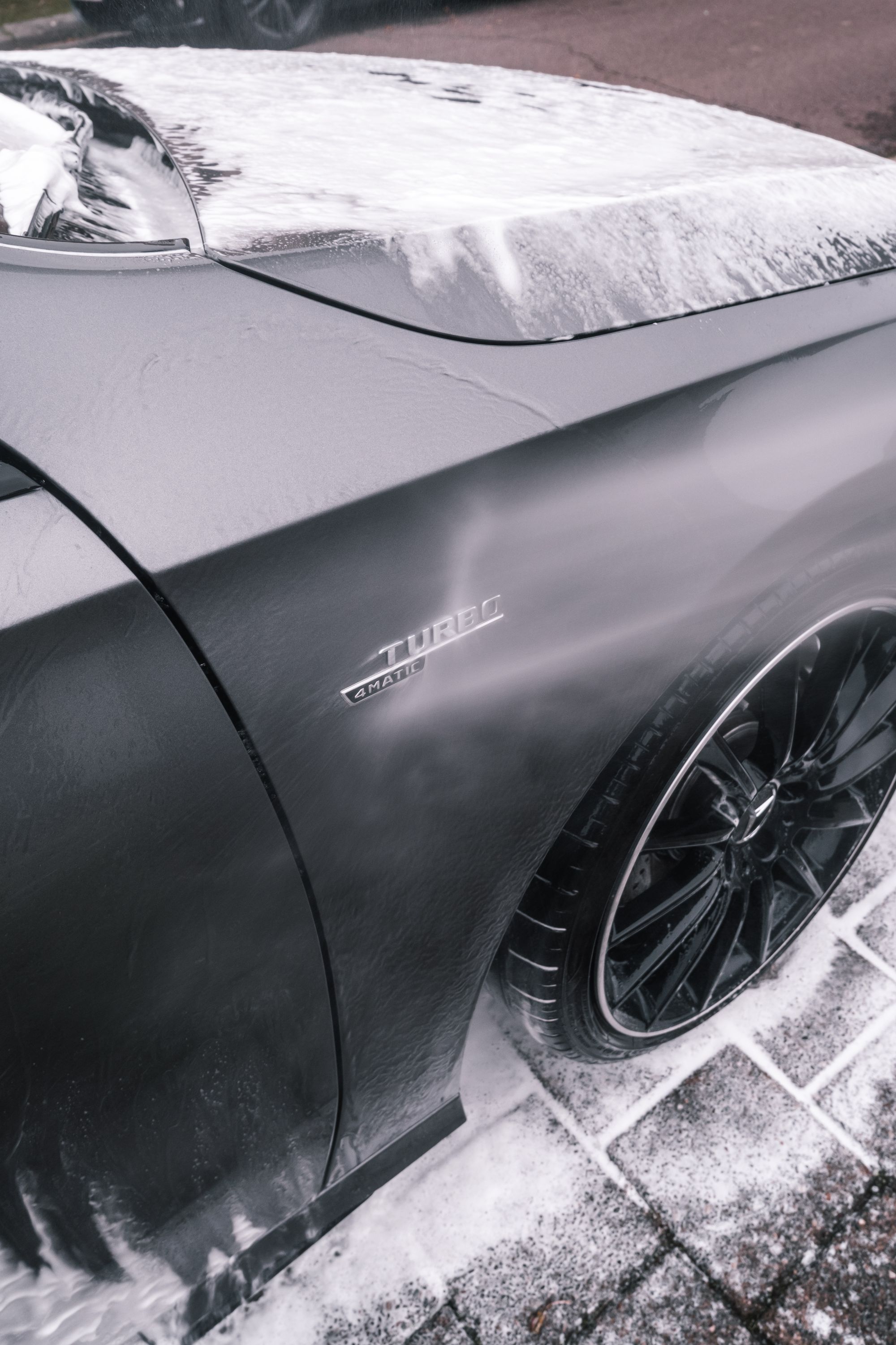 A dark car covered with wash foam